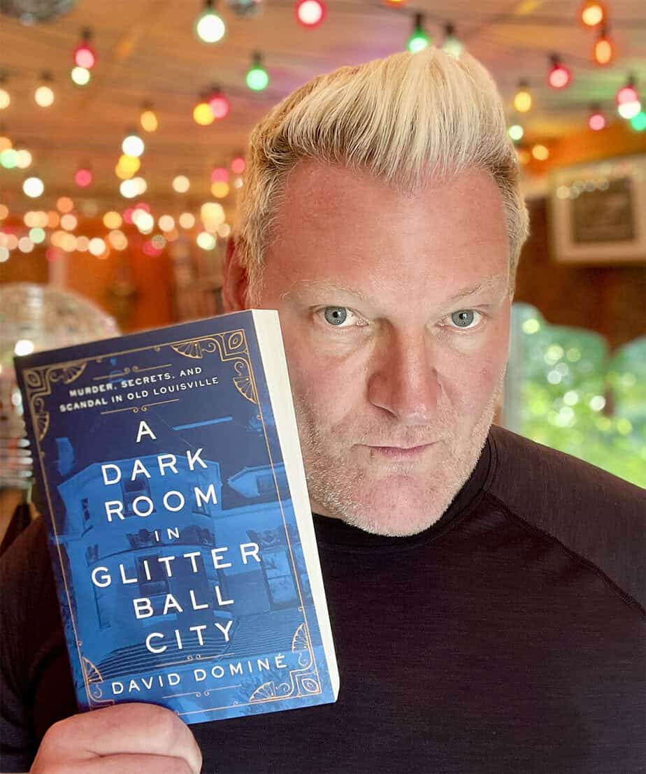 David Dominé holding his book A Dark Room in Glitter Ball City