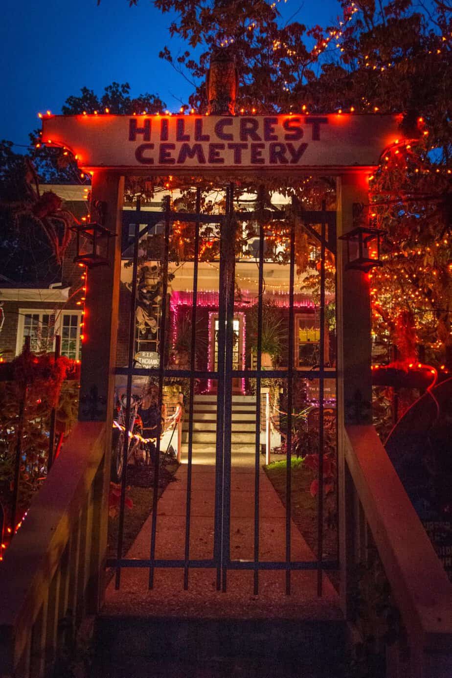 Halloween on Hillcrest Avenue in Crescent Hill, Louisville: a home decorated as Hillcrest Cemetery with orange lights and an iron gate.
