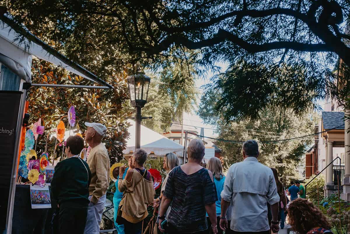 Crowds browsing artist booths beneath a gas lamp at the St. James Court Art Show in Old Louisville.